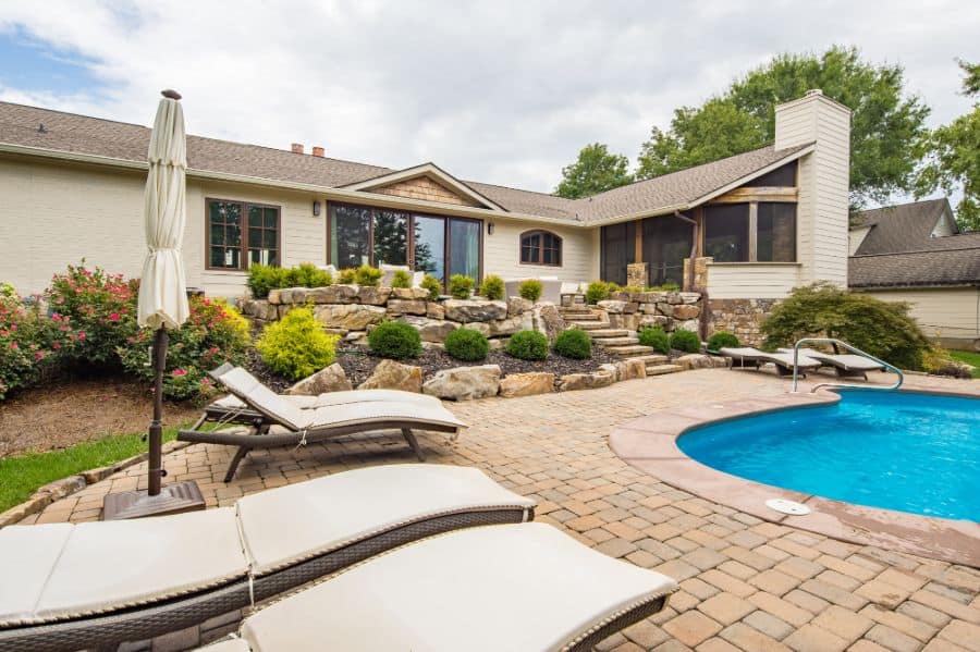 large backyard paver pool patio with sun loungers