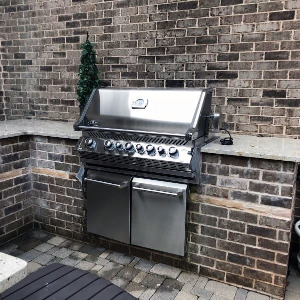 Built-in stainless steel grill set in a brick patio cooking station