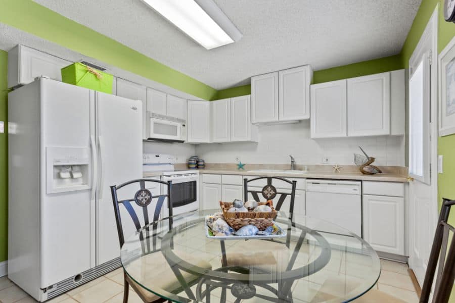 white cabinet kitchen green walls glass table