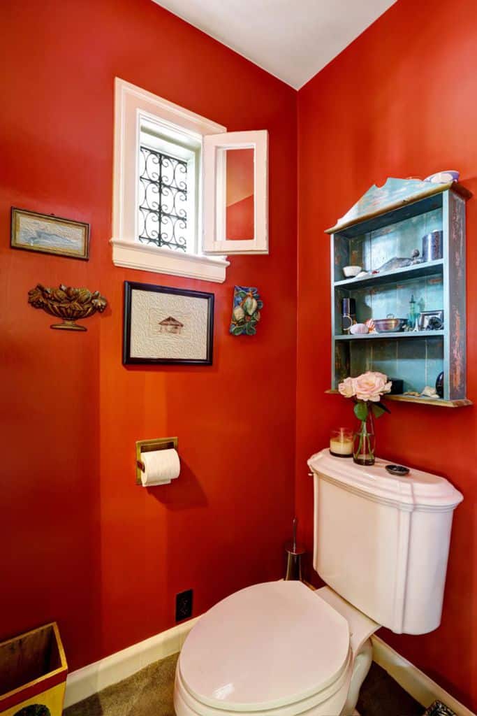 bright red powder room with vintage wall decor 
