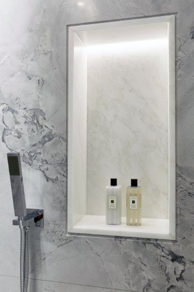 Modern shower with a recessed niche illuminated by bright white LED lights, showcasing sleek storage for bottles