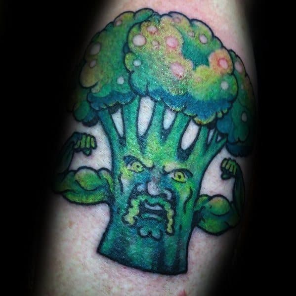 Muscular broccoli tattoo with a fierce expression, flexing its arms in a bold, colorful design that blends humor and strength.