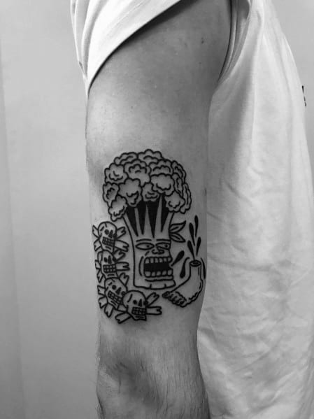 Bold black ink broccoli tattoo on the upper arm, featuring a tribal-inspired design with expressive details for a unique and edgy look.