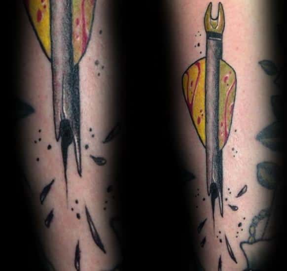 Colorful tattoo of an arrow with yellow and red fletching piercing the skin, with inked cracks and splinters adding a dynamic effect.