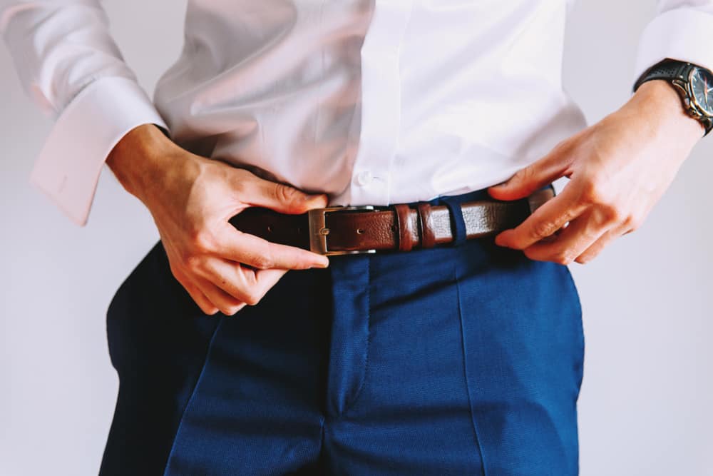 man wear brown belt on blue pant