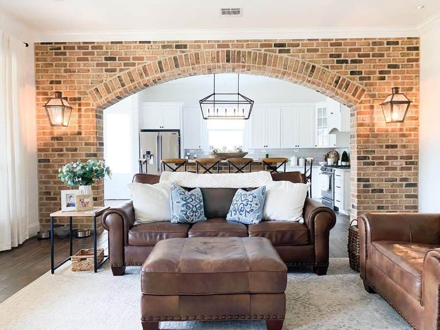 brick feature wall brown leather sofa and lounge chair open kitchen living room