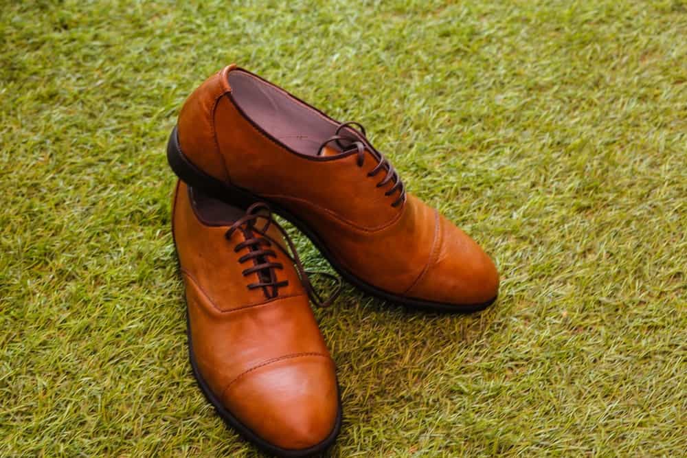pair of brown oxford shoes, photographed on green grass