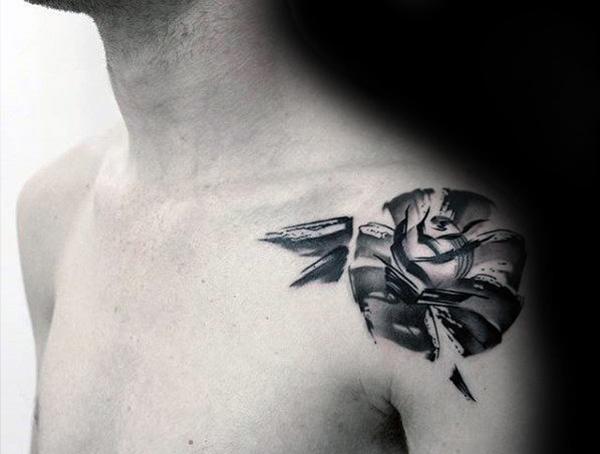 Black and grey abstract tattoo of a rose on the shoulder, featuring a fragmented design with sharp edges and dynamic shading.