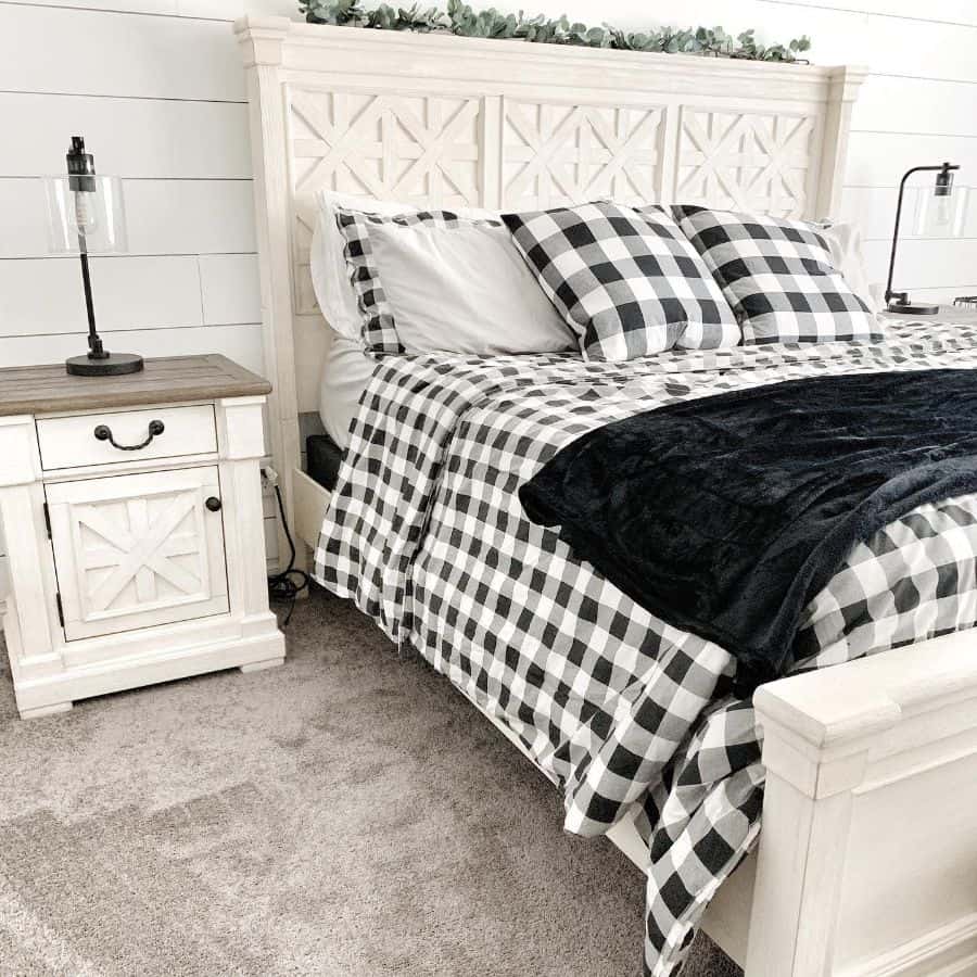 Farmhouse bedroom with a white wooden bed, black and white plaid bedding, two bedside tables, and modern lamps