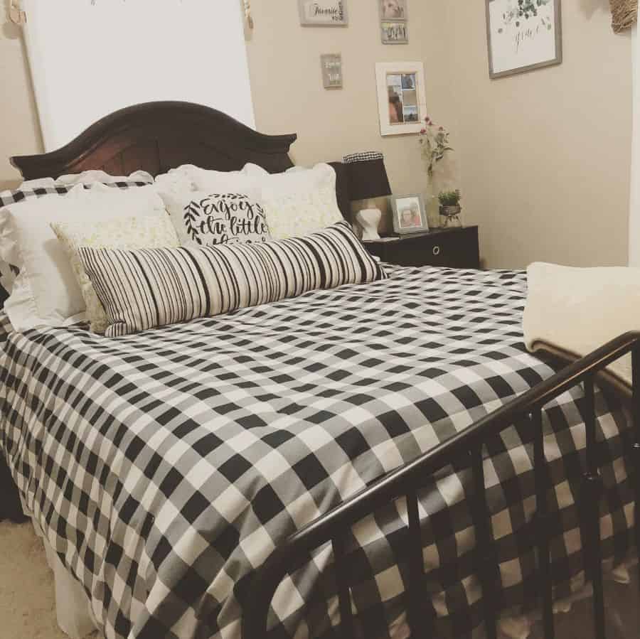 Cozy farmhouse bedroom with a checkered bedspread, decorative pillows, and framed art on the walls