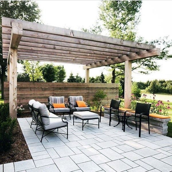 Wooden pergola pavilion with cushioned seating, modern patio design, and a privacy screen in a garden setting.