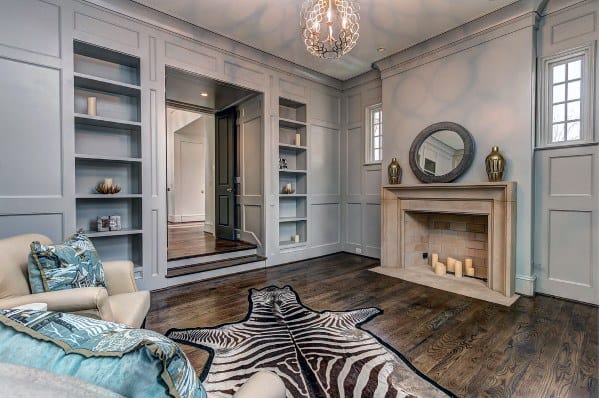 Elegant living room with built-in bookcases, zebra rug, modern chandelier, and a fireplace decorated with candles