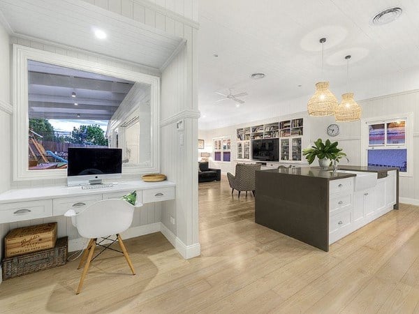 Modern home interior with a built-in desk, computer, kitchen island, and wicker pendant lights