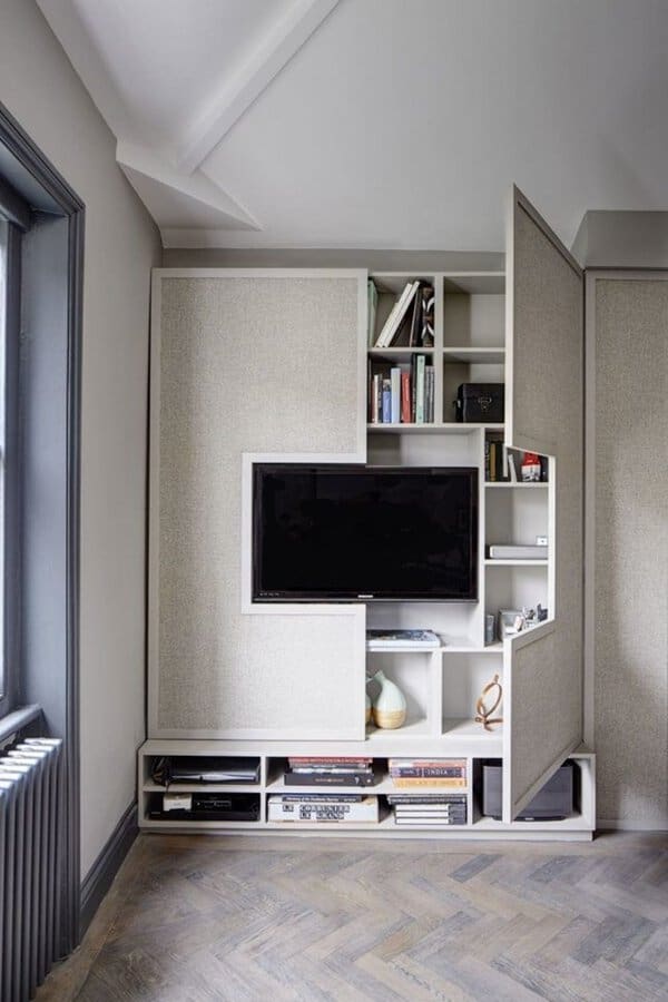 Modern built-in storage unit with hidden shelves and a concealed TV in a minimalist living room.