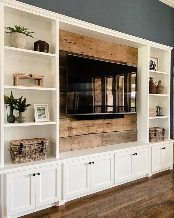 White built-in shelves with a rustic wood accent wall and a mounted TV in a modern living room.