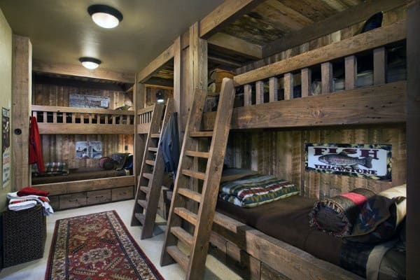 Rustic wooden bunk beds with ladders, cozy bedding, built-in storage, and vintage decor in a warm, cabin-style room