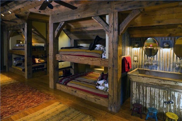 Rustic bunk beds in a cozy cabin setting with warm lighting, wooden beams, and an integrated sink area for functionality