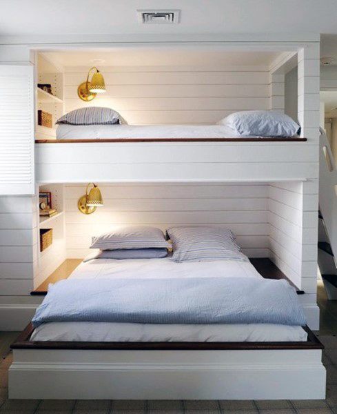 Built-in bunk beds with shiplap walls brass wall sconces and cozy bedding.