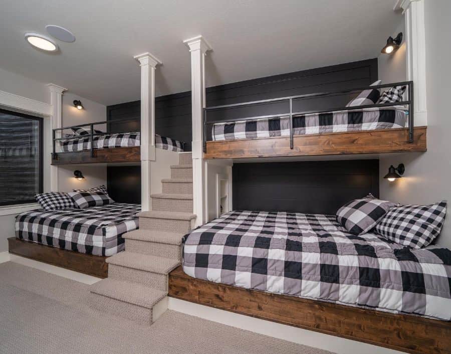 Four rustic bunk beds with black and white checkered bedding and built-in stairs in a cozy room.