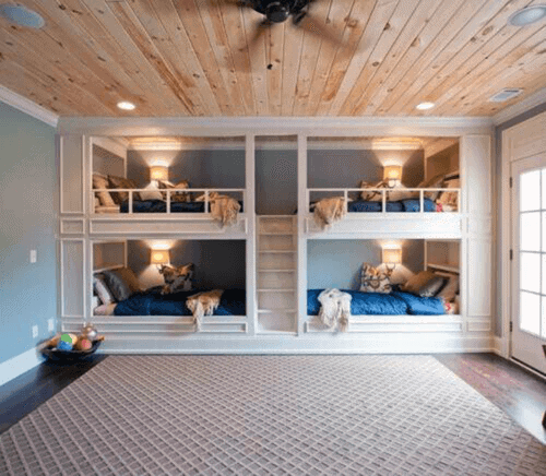 Cozy room with wooden ceilings, featuring bunk beds with blue bedding and floor rug