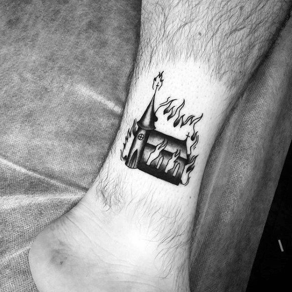 Small burning church tattoo with simple black ink flames and minimal shading. Placed just above the ankle for a subtle look.