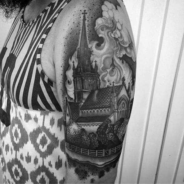Detailed church tattoo with gothic architecture and swirling smoke. Surrounded by trees and a fence, placed on the upper arm.