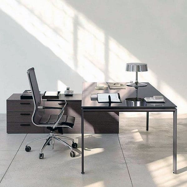 Minimalist office setup with a desk, chair, lamp, and neatly arranged books under soft, natural light