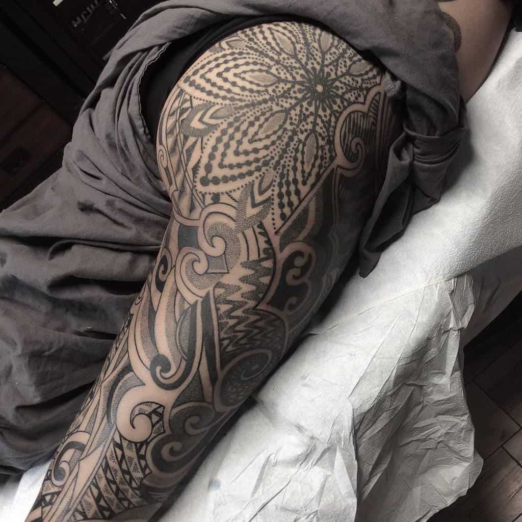 Intricate tribal leg sleeve tattoo featuring bold patterns and detailed swirling designs