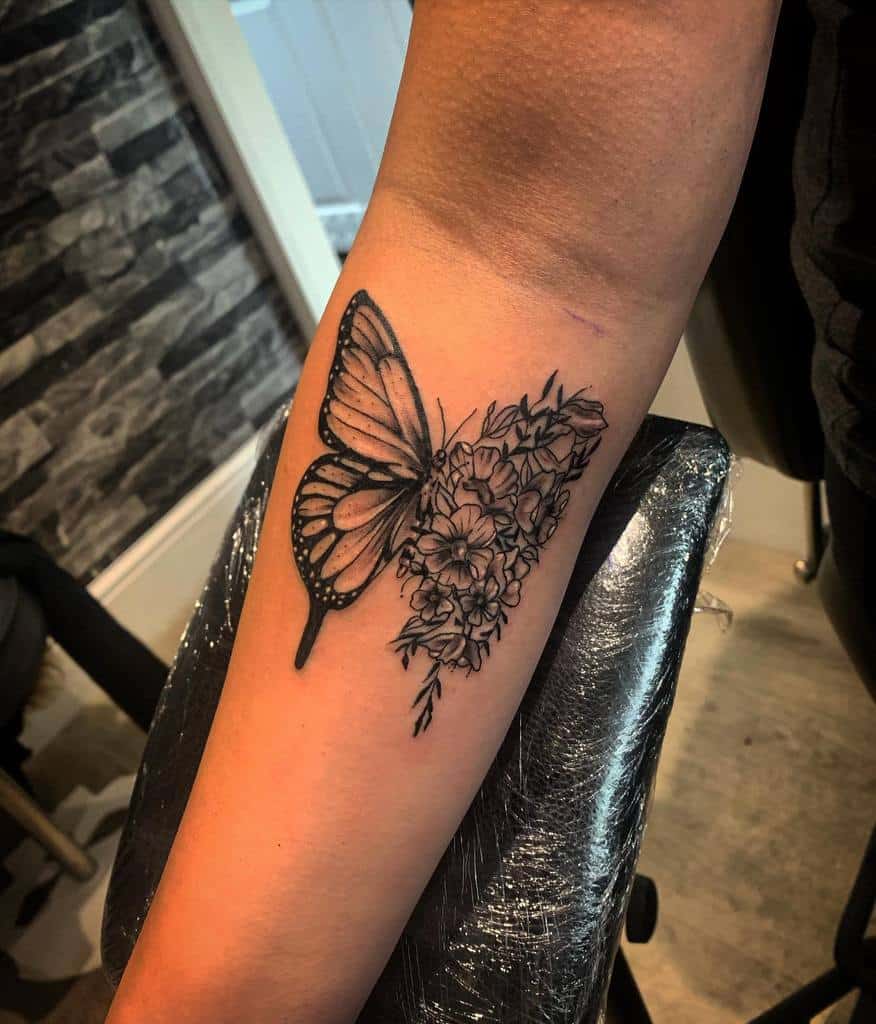 Forearm tattoo of a half-butterfly and half-flower design in black ink