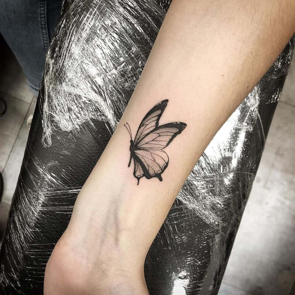 A black and white butterfly tattoo on a woman's wrist