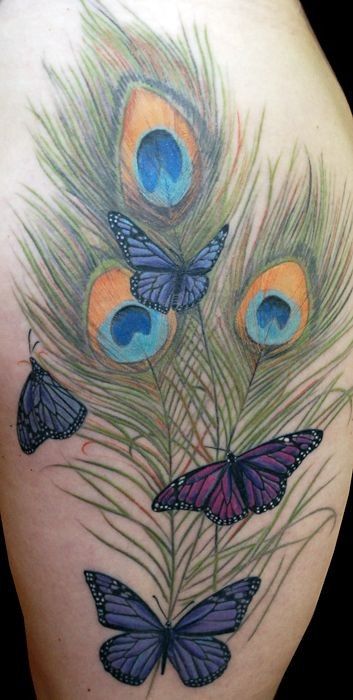 Colorful tattoo featuring multiple peacock feathers with blue and gold eye patterns, surrounded by detailed purple and blue butterflies.