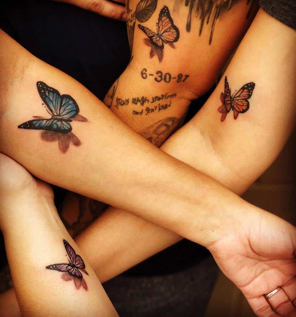 Matching sibling tattoos featuring colorful butterflies in different shades, symbolizing transformation, freedom, and connection