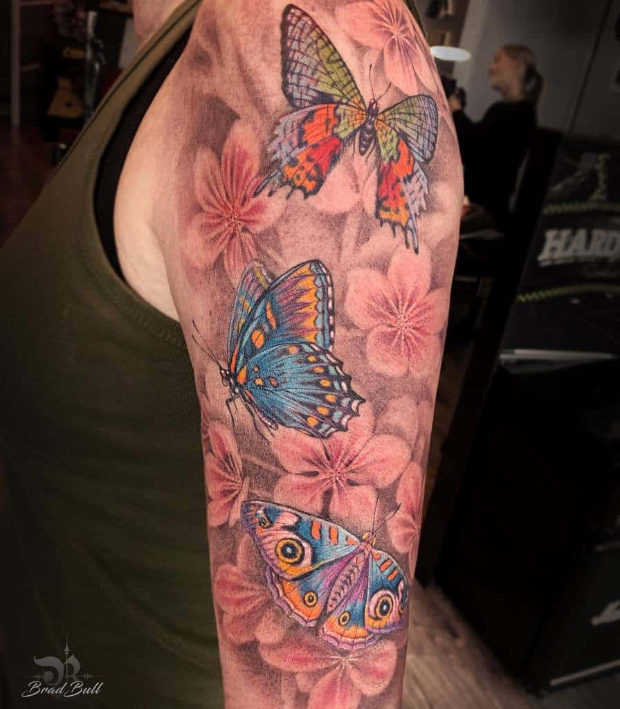 Upper arm tattoo with colorful butterflies and pink flowers