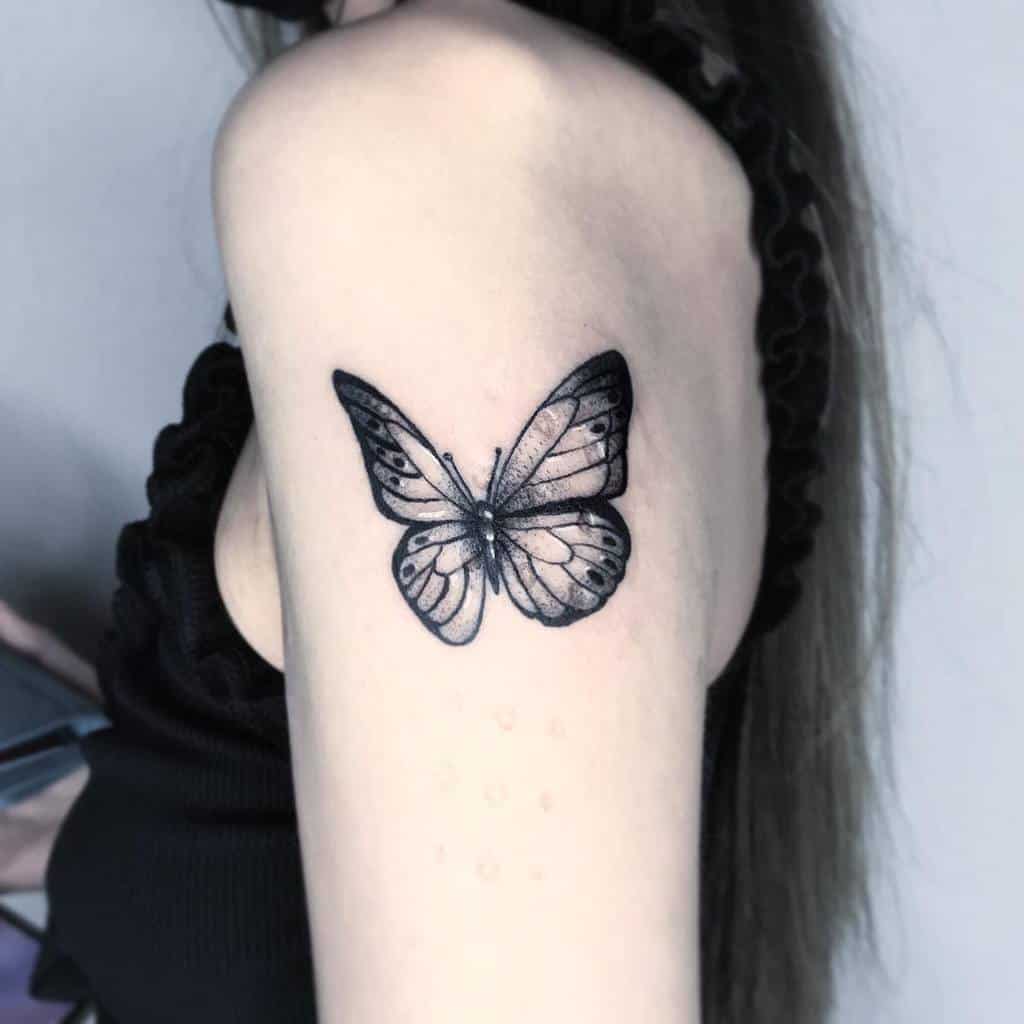 Black butterfly tattoo on a woman's upper arm