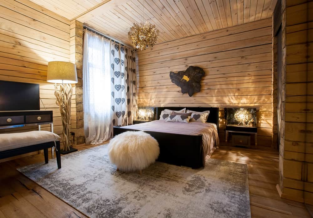 wood panel bedroom with floor rug and chandelier
