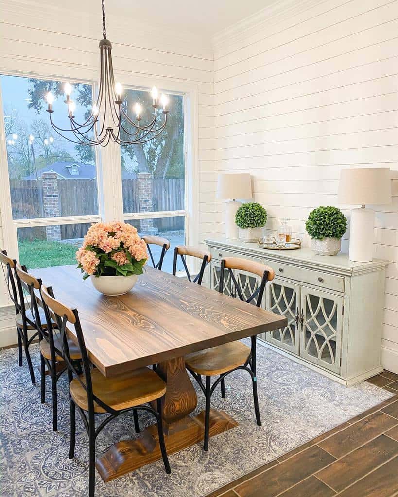 shiplap white walls green cabinet wood dining room table and chairs chandelier flowers 