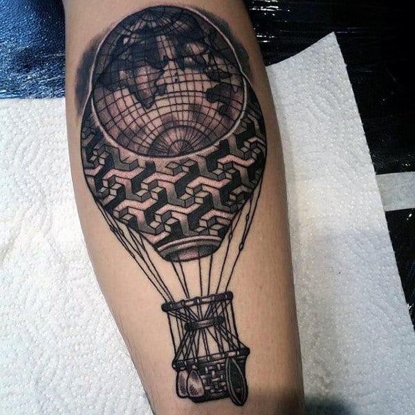 Black and grey calf tattoo of a hot air balloon with a globe at the top and intricate geometric patterns, detailed with fine linework