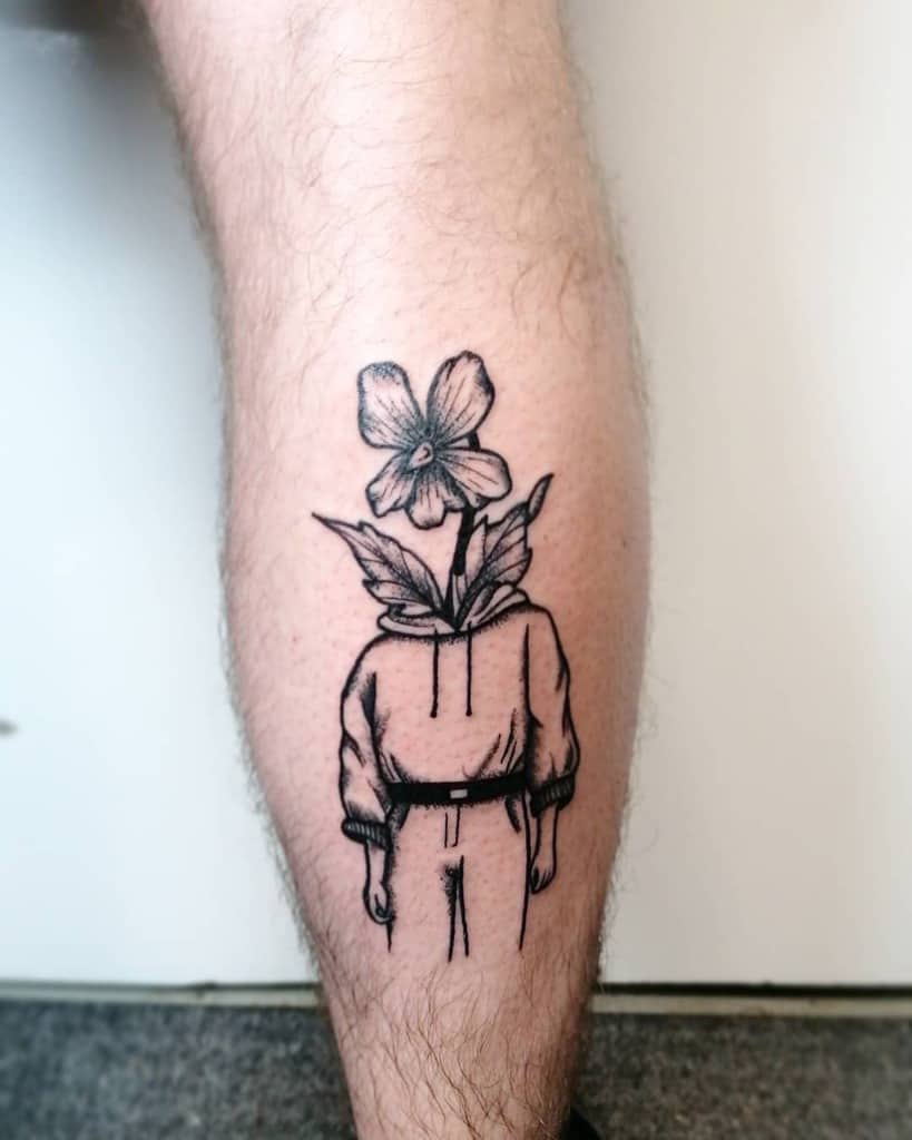 Black ink tattoo of a headless figure in casual clothes with violet flowers growing from the neck, symbolizing nature and self-growth