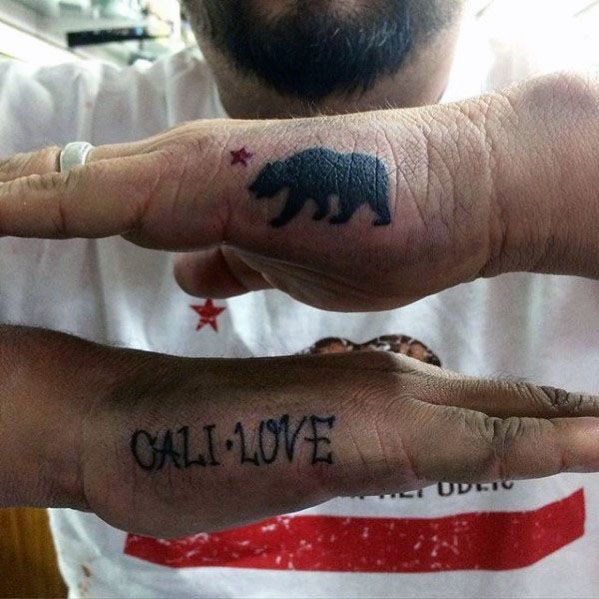 Side hand tattoo for men with the phrase CALI LOVE in bold font, paired with a bear and star tattoo on the opposite hand.