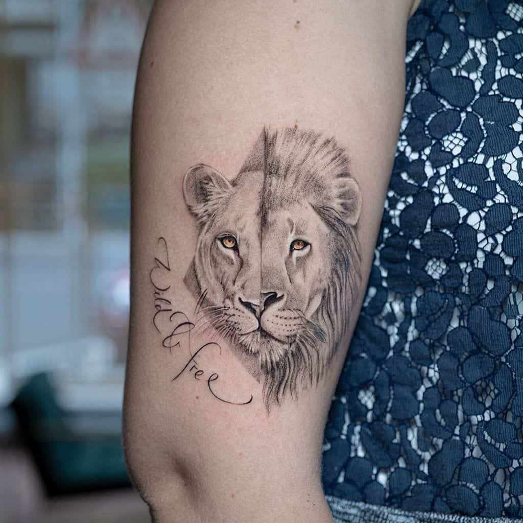 Realistic split-design lion and lioness tattoo on the upper arm, featuring fine shading, golden eyes, and the phrase 'Wild & Free' in cursive.