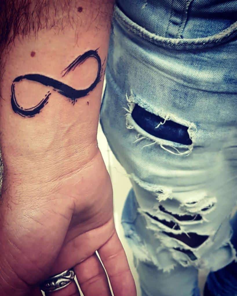 A bold and minimalist infinity tattoo, inked in black, placed on the wrist for a simple yet timeless design.