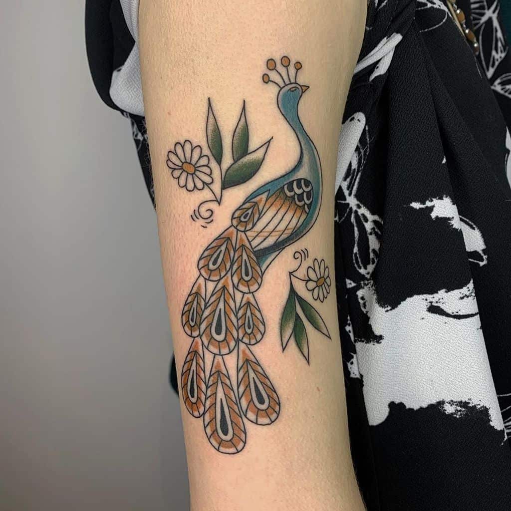 Colorful peacock tattoo with intricate feather details, surrounded by leaves and flowers, on the forearm.