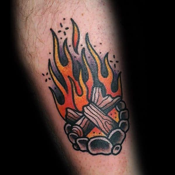 Bold traditional campfire tattoo with orange flames, stacked logs, and a ring of stones outlined in black.