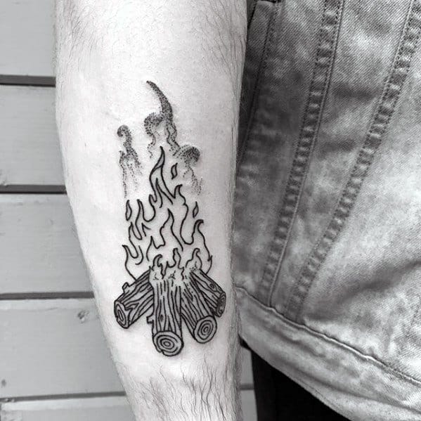 Minimalist blackwork campfire tattoo with detailed wood logs and stylized flame lines on the inner forearm.