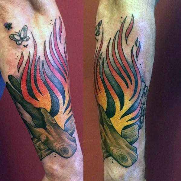 Vibrant campfire tattoo with stylized red and yellow flames, detailed logs, and fluttering butterflies on the forearm.