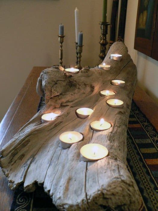 Tealight candles arranged on a rustic wooden log, with candlesticks in the background
