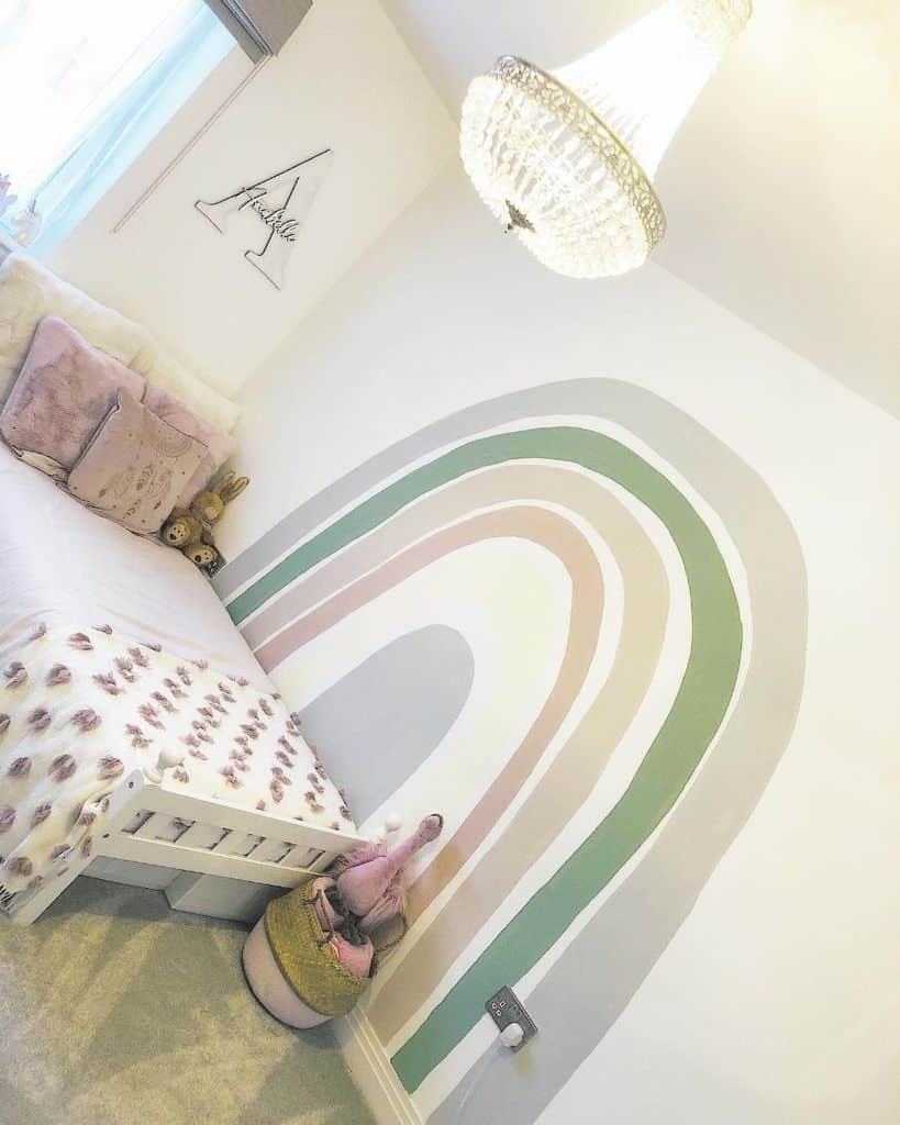 Bright kids' room with a rainbow mural, bed, decorative pillows, and a chandelier