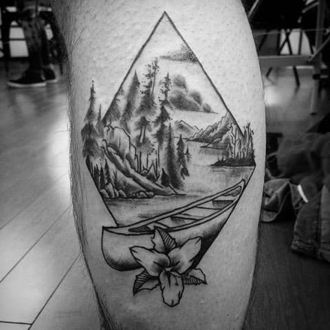 Alt text: Geometric tattoo of a canoe on a lake surrounded by trees and mountains, with a flower at the base.