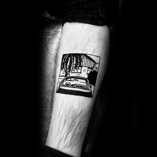 Black and white tattoo of a car with palm trees and buildings in the background on an arm