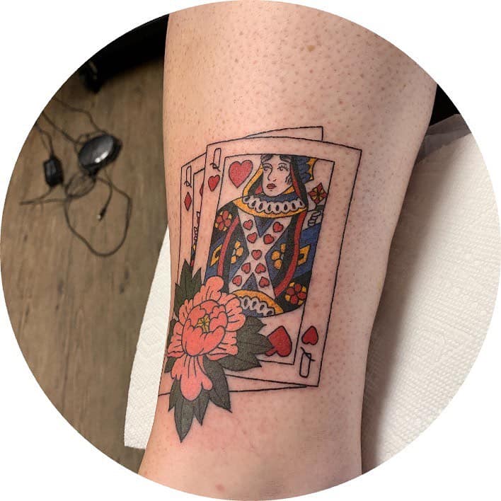 Queen of Hearts tattoo featuring layered playing cards with a floral accent